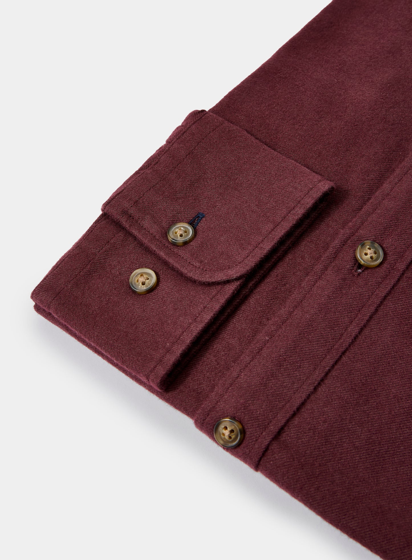 Close-up of a burgundy shirt with buttons on a light gray background