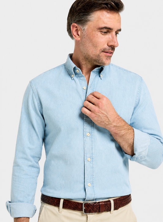 A man wearing a light blue long-sleeve button-down shirt, paired with beige trousers and a brown belt, shown against a plain light gray background.