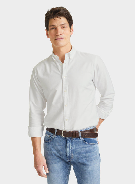 Man wearing a men's white Oxford button-down shirt with blue jeans, front view