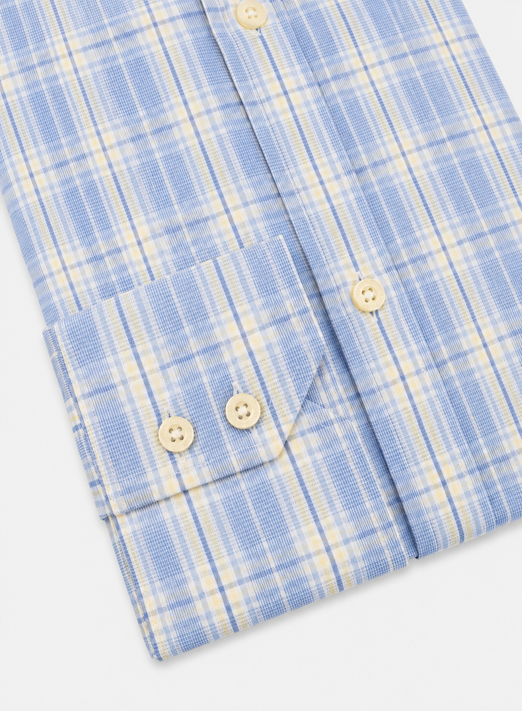 Close-up of a light blue and cream plaid button-down shirt showing the pocket, buttons, and fabric texture.