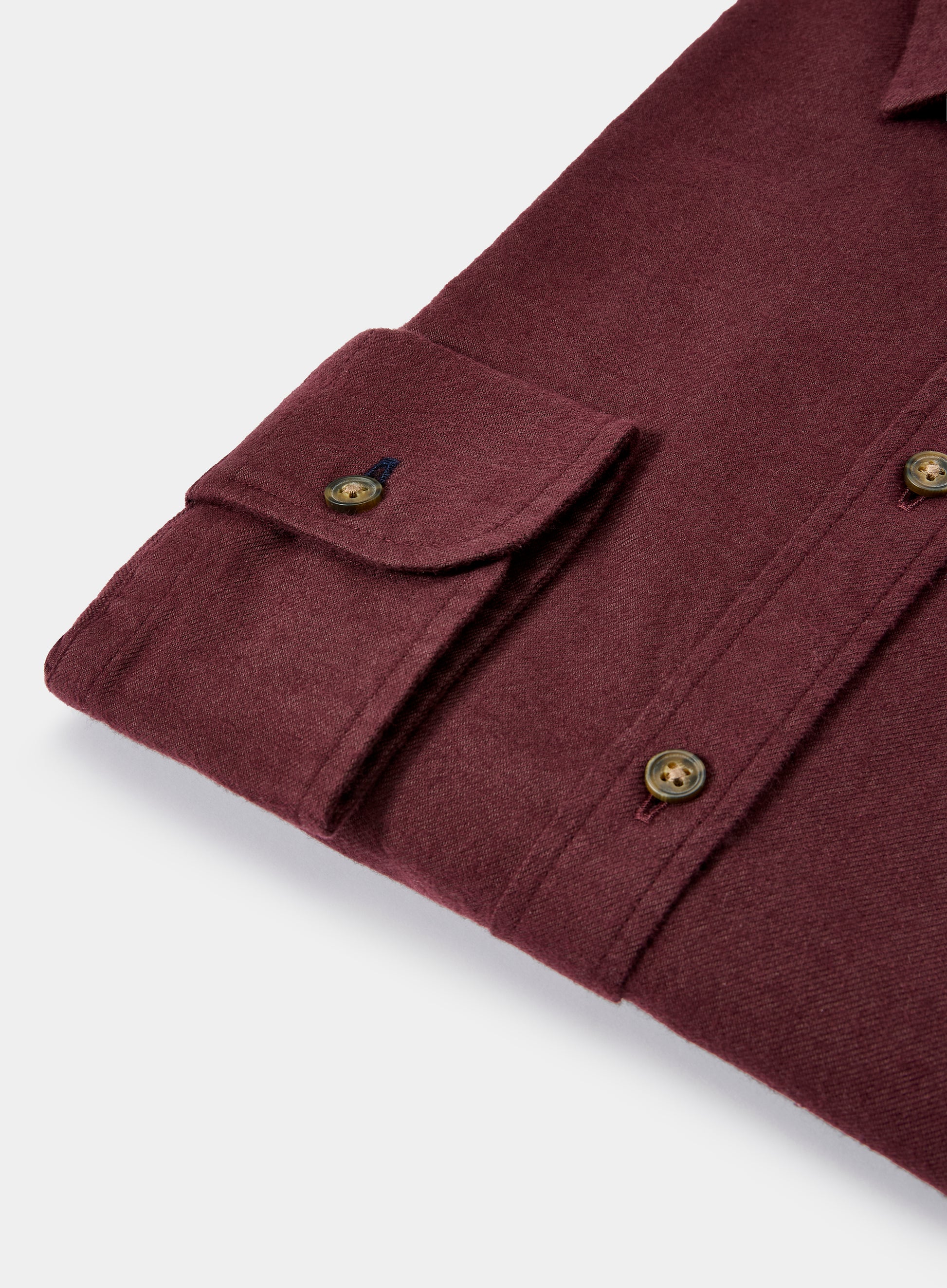 Close-up of a burgundy shirt with button details on a light gray background