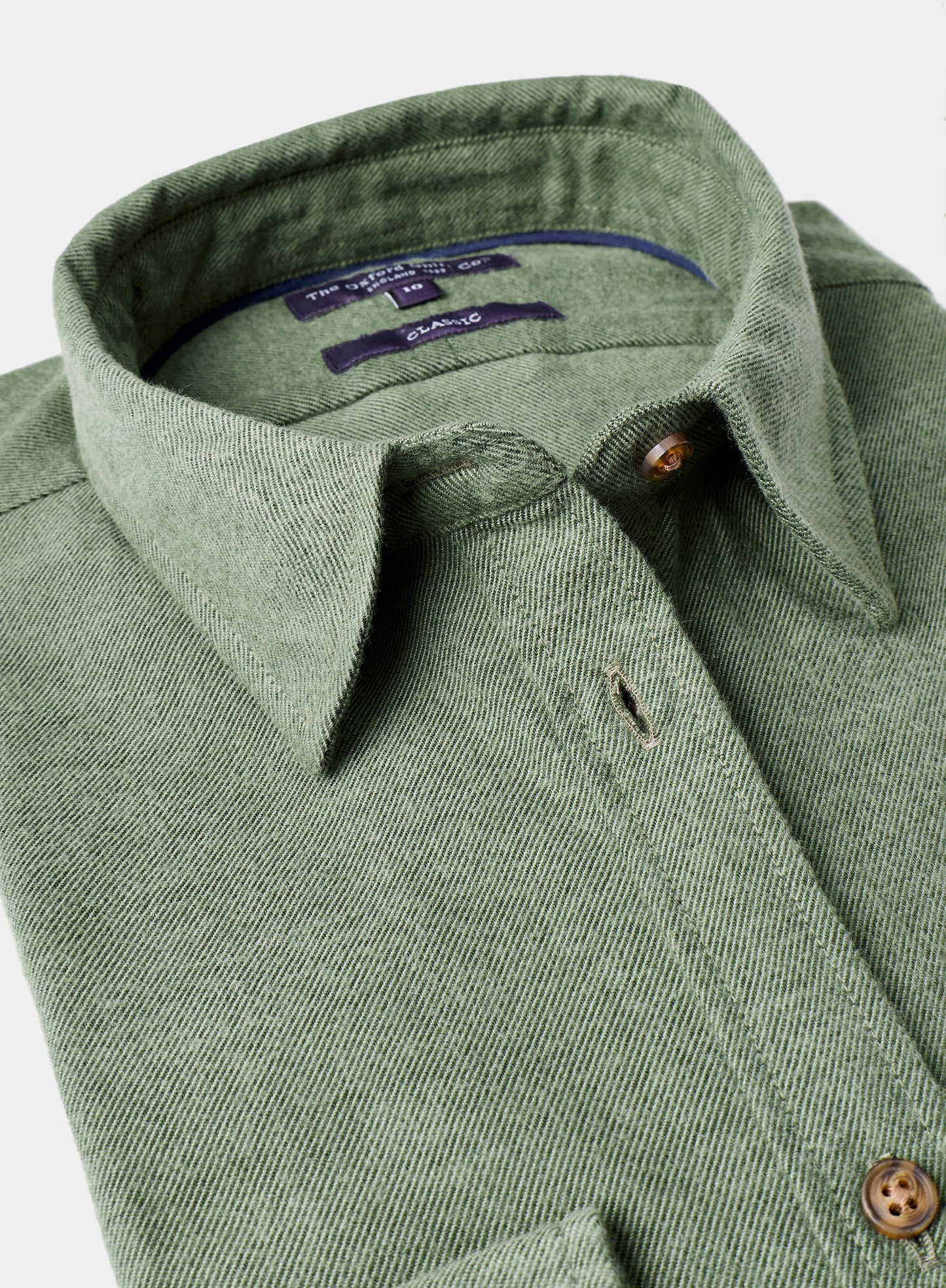 Close-up of a green shirt collar with buttons on a light gray background