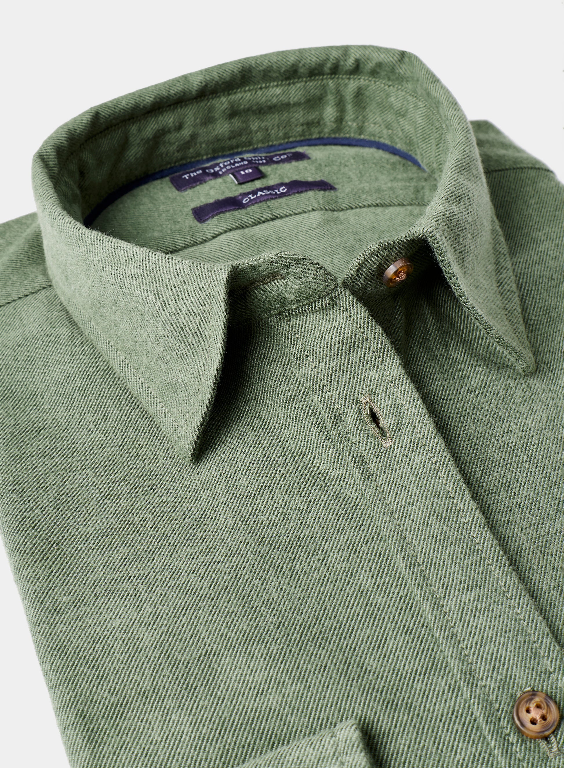 Close-up of a green shirt collar with buttons on a light gray background