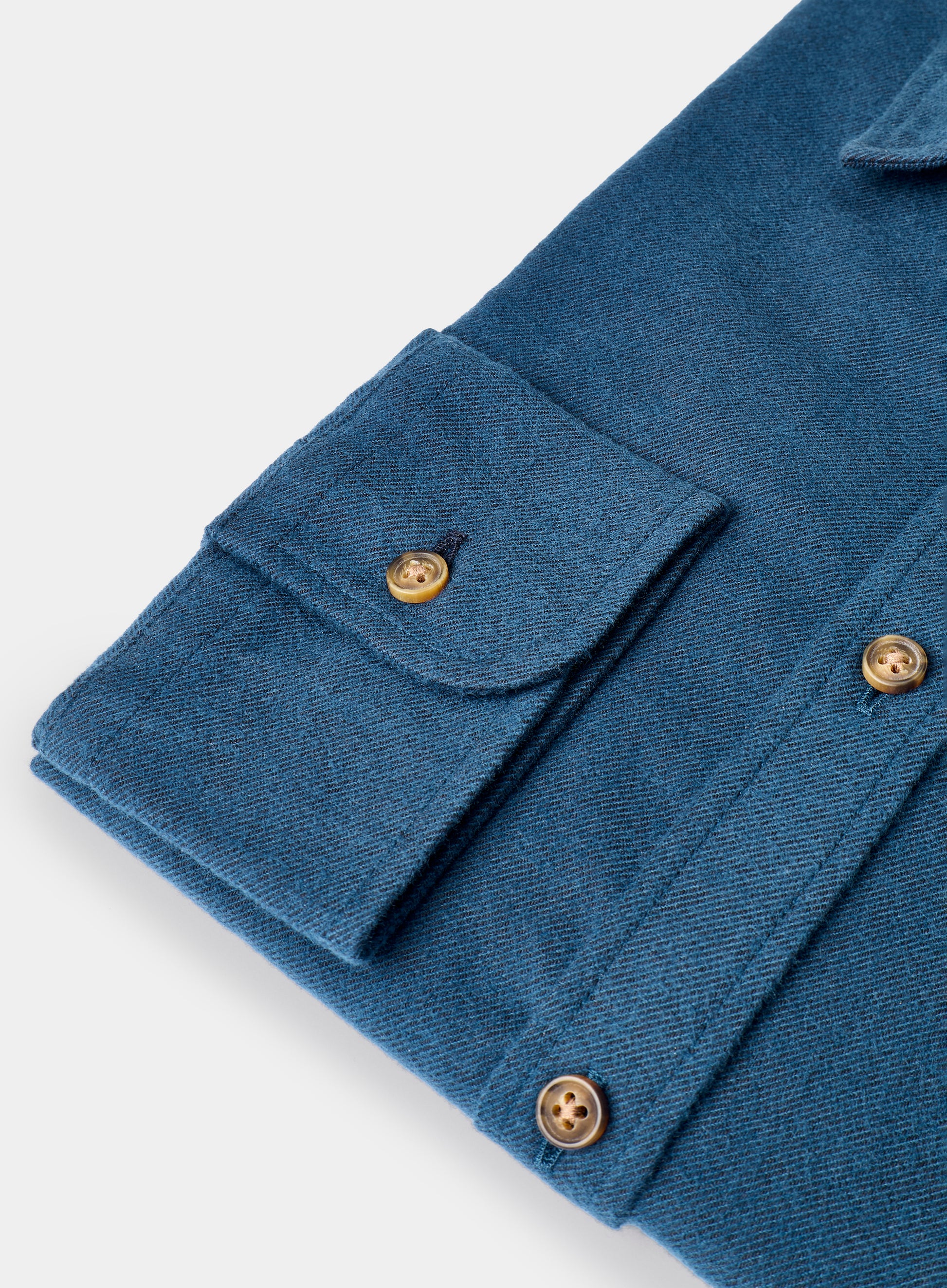 Close-up of a blue fabric with gold buttons on a white background
