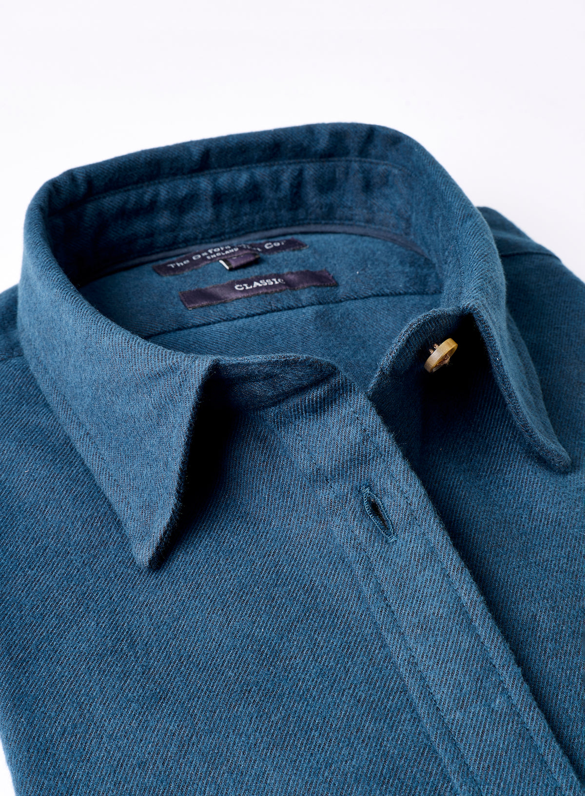 Close-up of a blue shirt with a collar and button on a white background