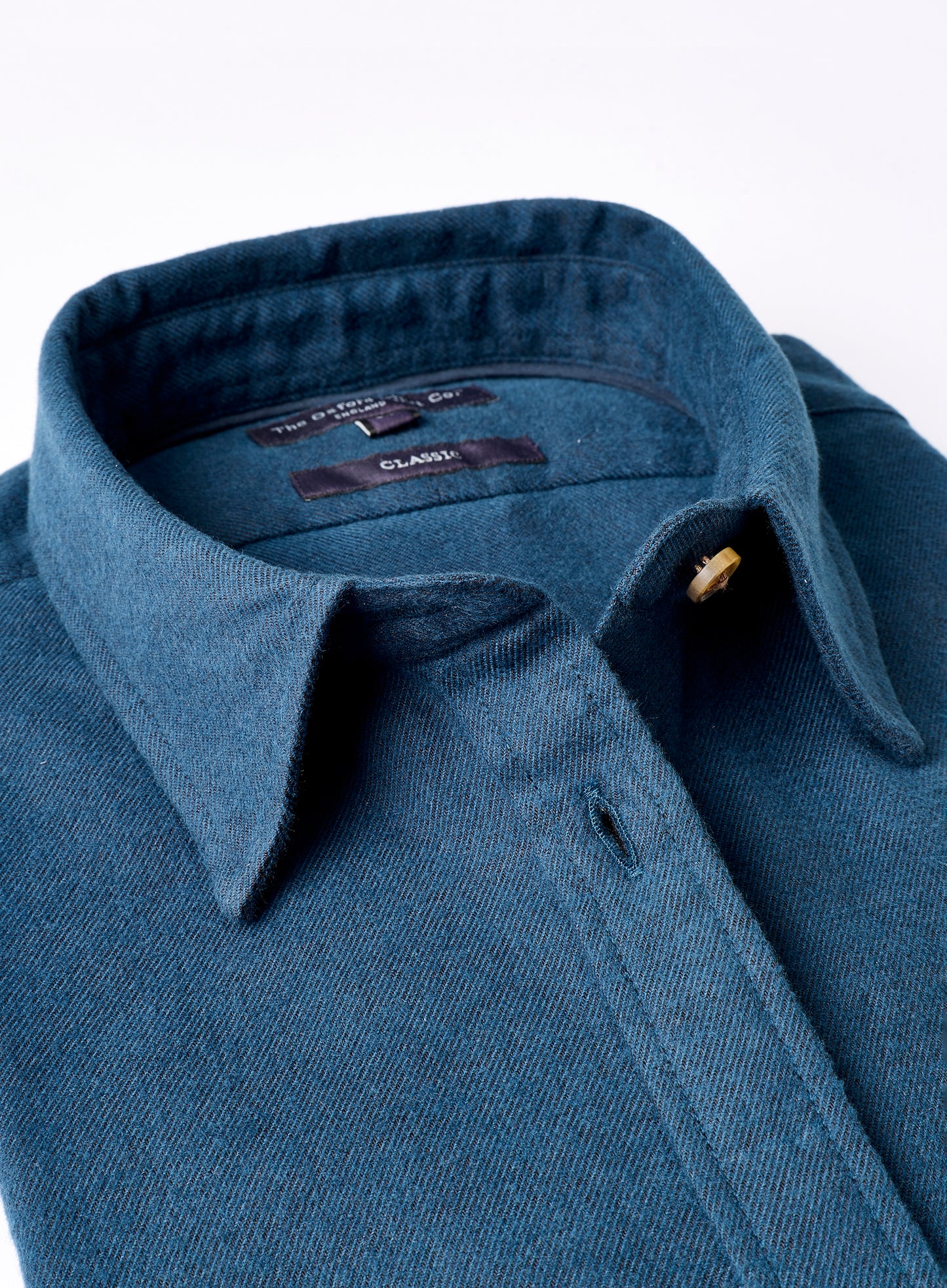 Close-up of a blue shirt with a collar and button on a white background
