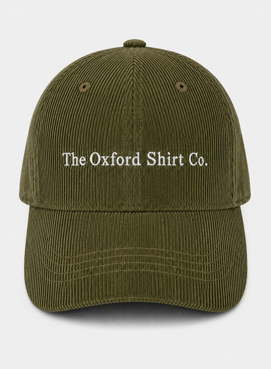 An olive green corduroy baseball cap with 'The Oxford Shirt Co.' embroidered in white on the front, set against a light gray background.