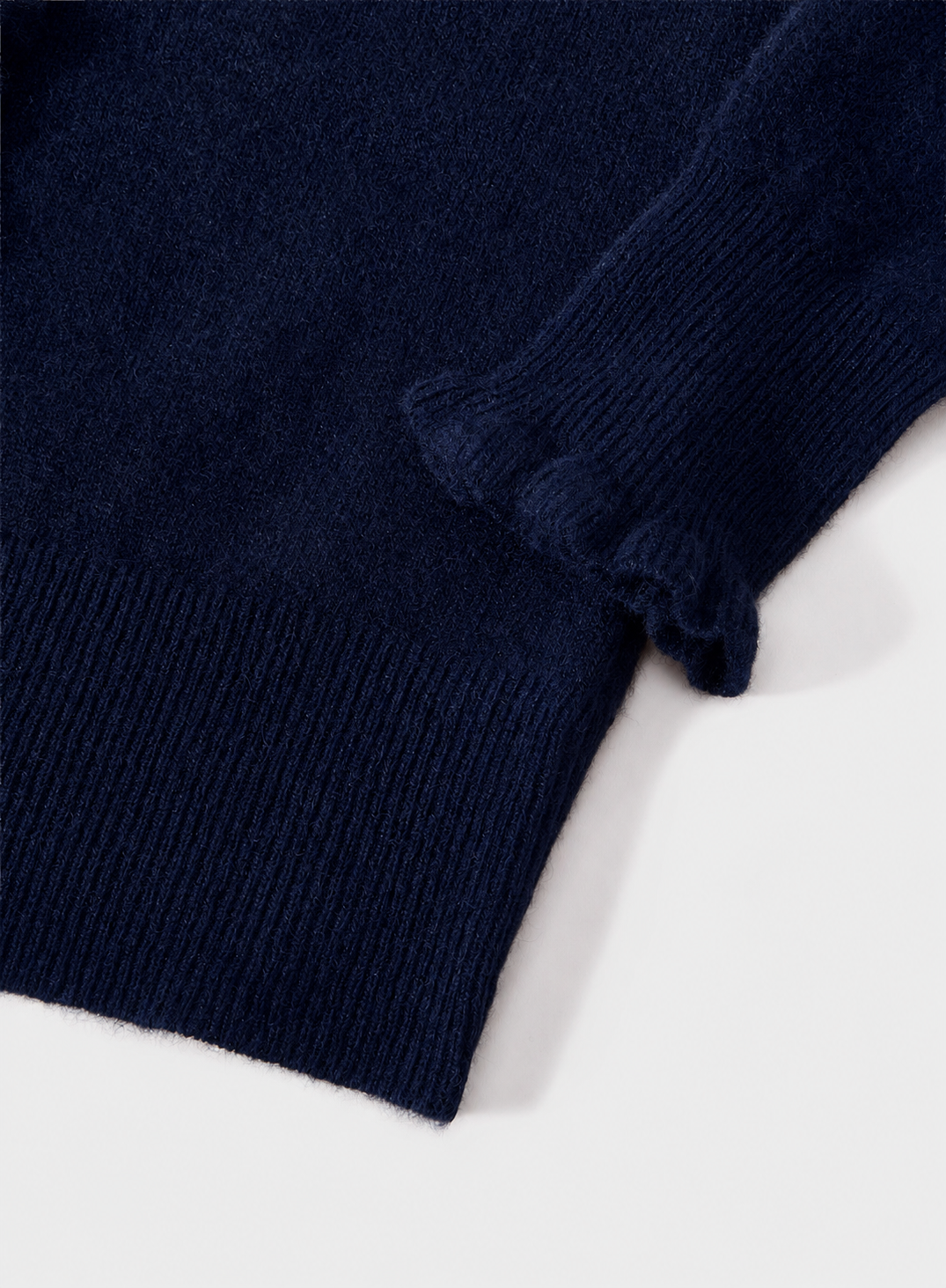 Close-up of a dark navy blue ribbed knit fabric, showing the texture and folded cuff detail on a light gray background.