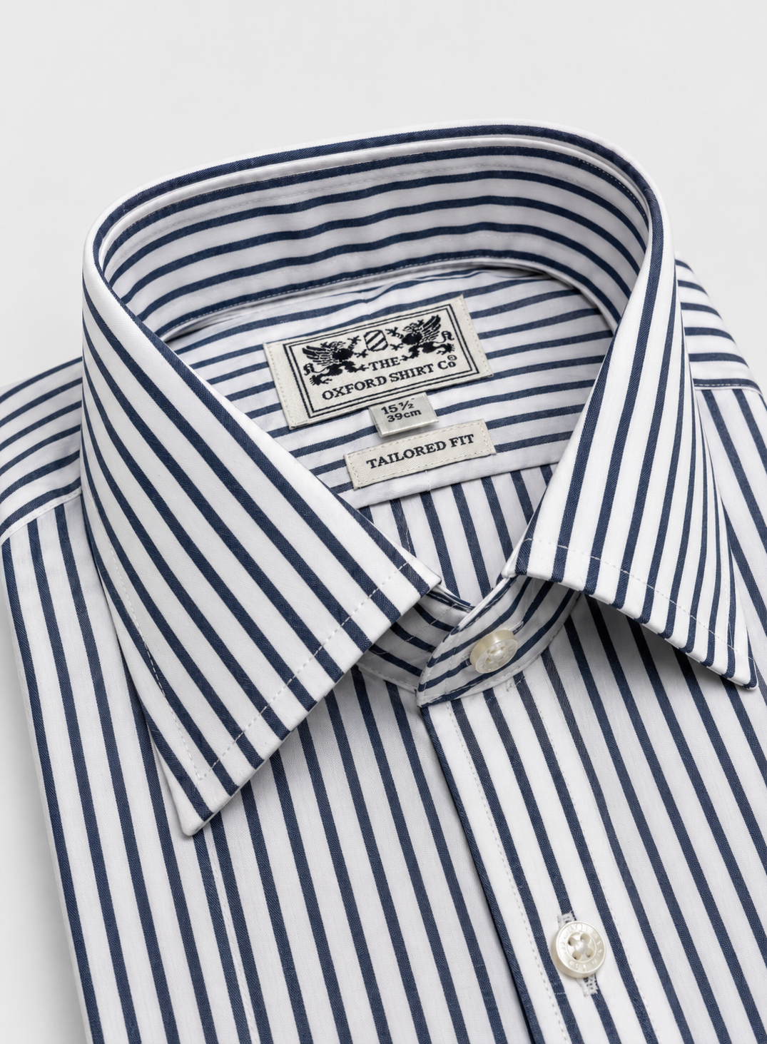 Close-up of a folded dress shirt collar showing the brand label 'Oxford Shirt Co' and the striped pattern of navy blue and white.