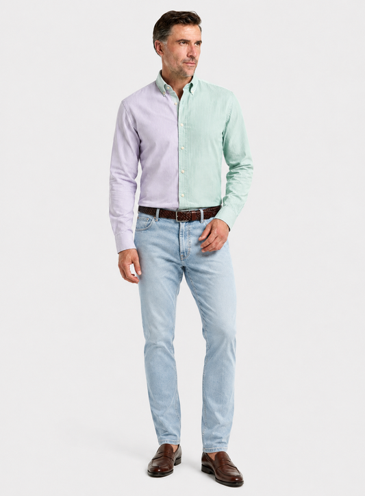 A man modeling a light purple and mint green color-blocked long-sleeve button-down shirt, paired with light blue jeans, a brown belt, and brown leather shoes, against a plain light gray background.