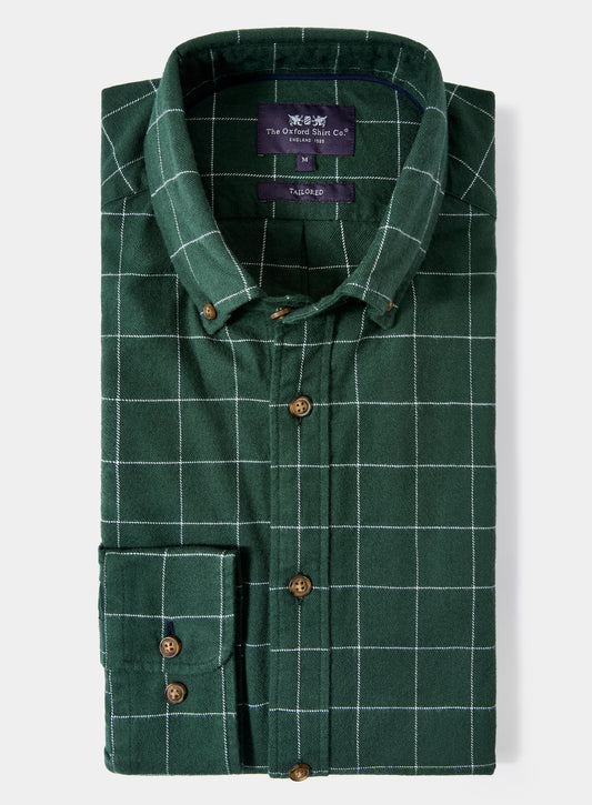 Green checkered shirt with brand label on a light gray background