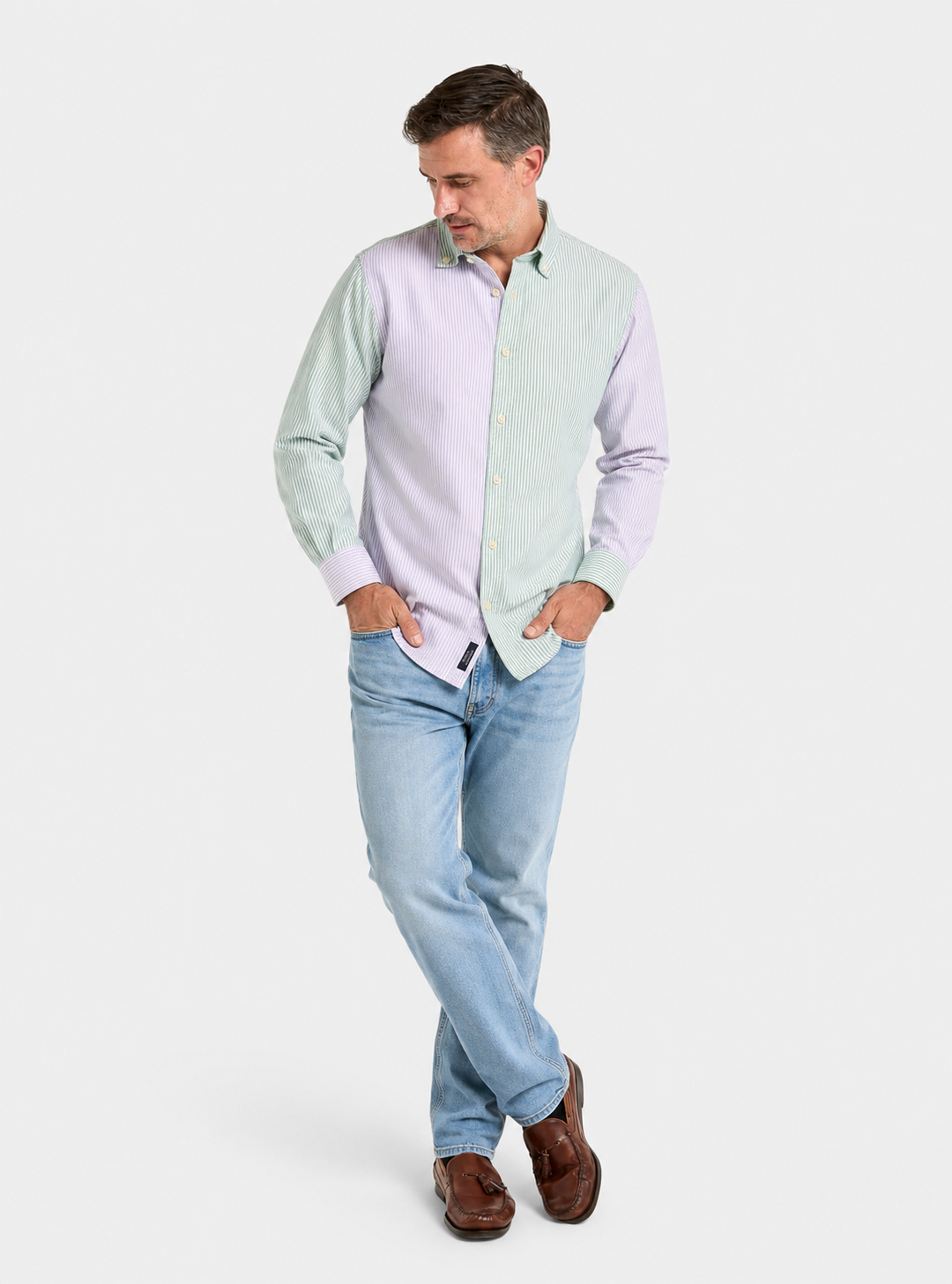 Man wearing a lilac and green patch stripe Oxford button-down shirt with blue jeans, relaxed full-length pose