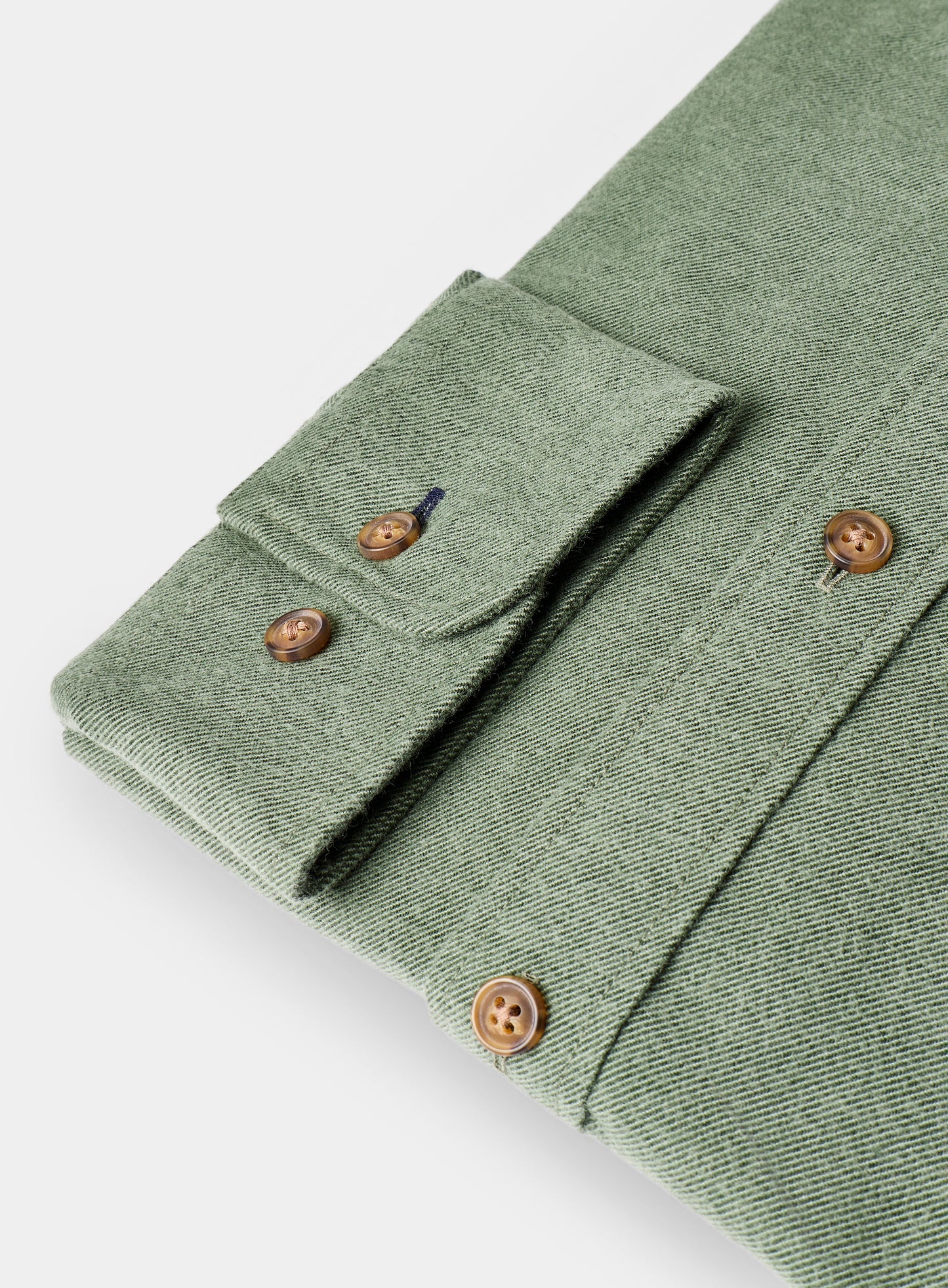 Folded green shirt with brown buttons on a white background
