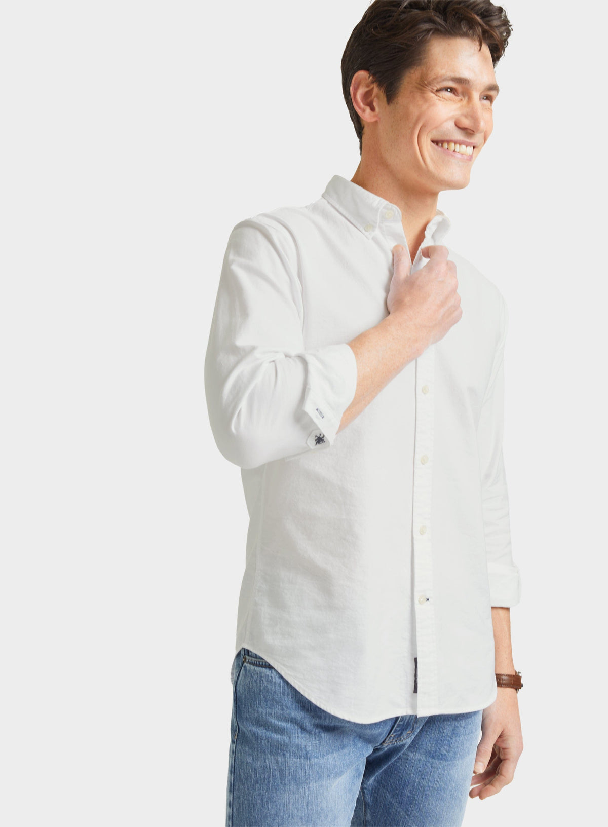 Man wearing a men's white Oxford button-down shirt with blue jeans, front three-quarter view