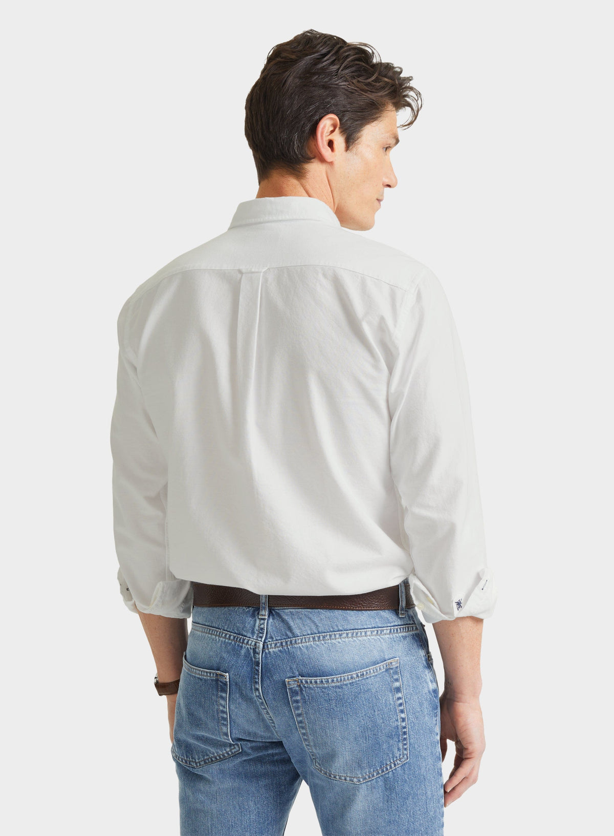 Rear view of man wearing a men's white Oxford button-down shirt with blue jeans
